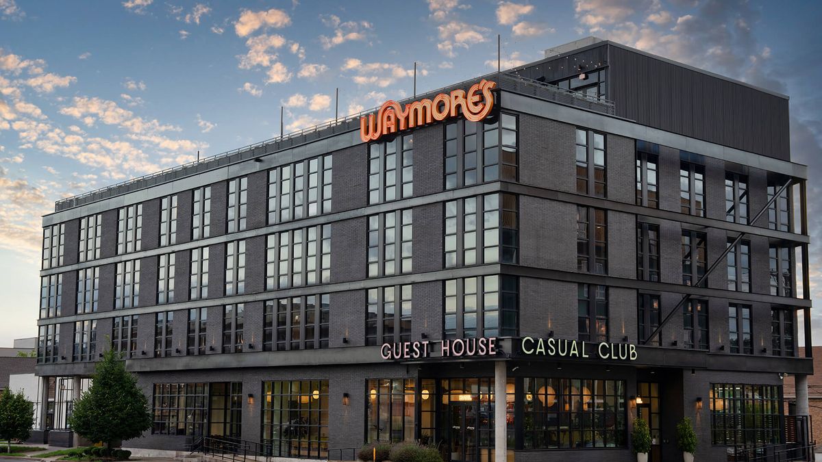 The Waymore — the guest house's dark brick exterior with its rooftop sign at sunset.